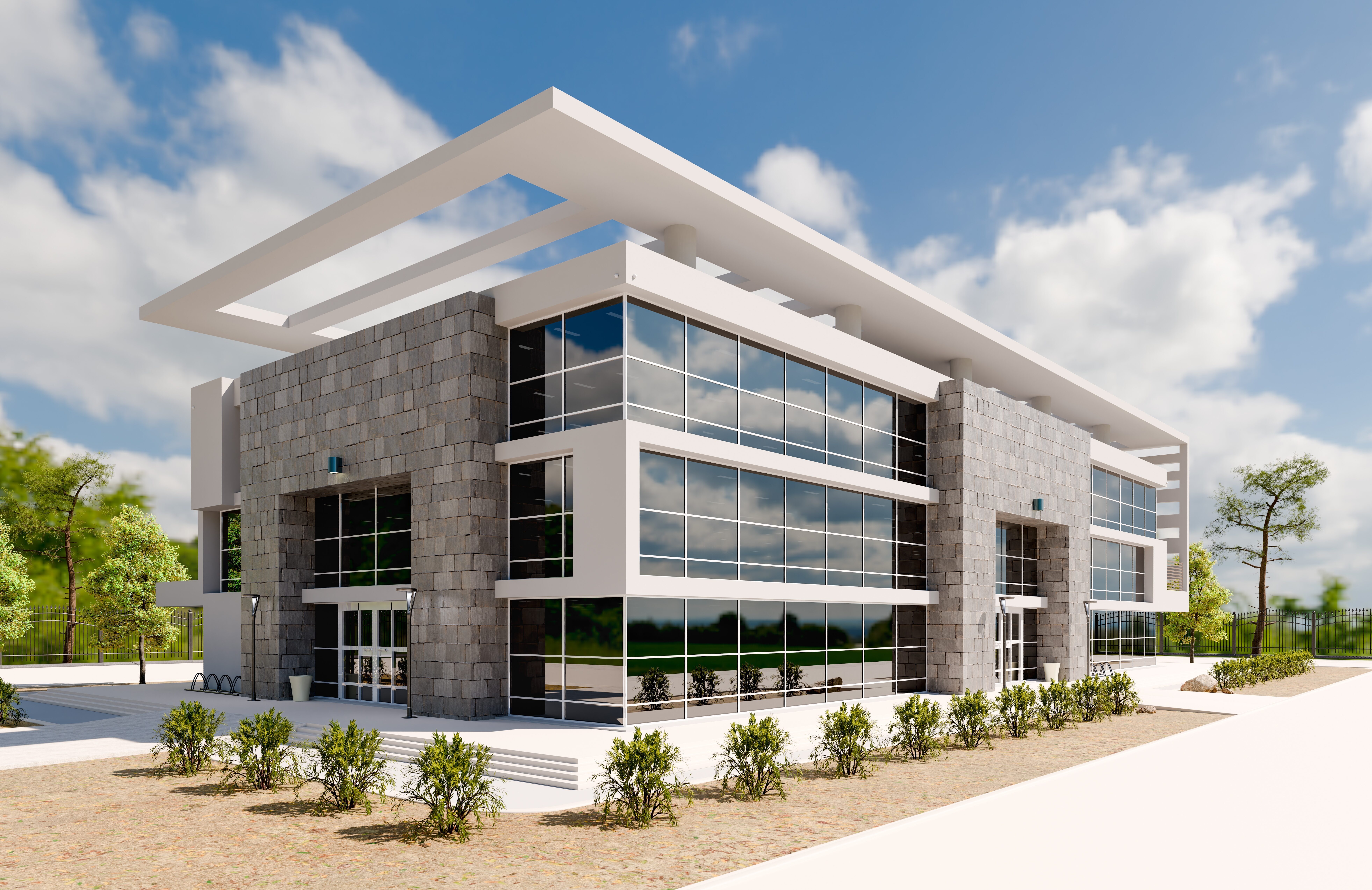 Modern two-story building with large glass windows, stone facade, and surrounding greenery under a blue sky.